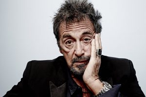 Al Pacino sits, his face leaning into one hand