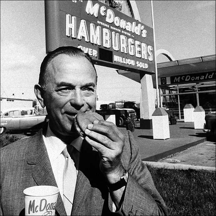 Portrait of McDonald's owner Ray Kroc eating hamburger in front of Neon sign outside restaurant (Photo by Art Shay//Time Life Pictures/Getty Images)