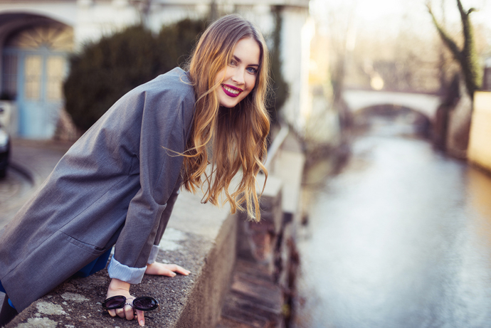 Beautiful smiling woman walking in the city near river embankment